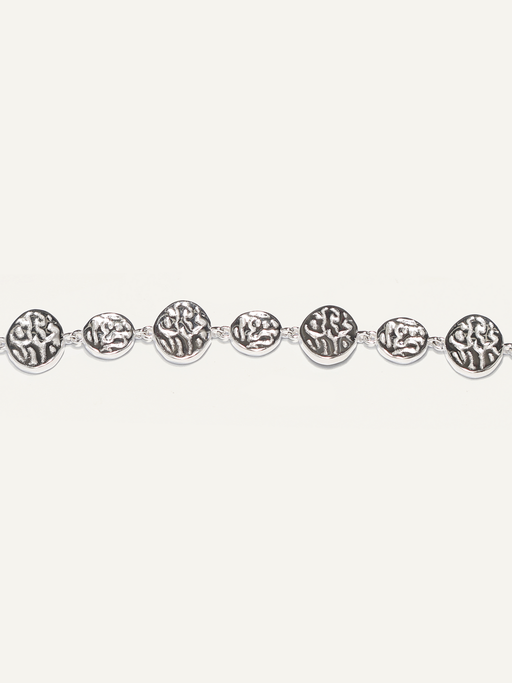 A silver chain bracelet featuring multiple oval links with embossed floral or leaf-like patterns, displayed horizontally against a solid off-white background.